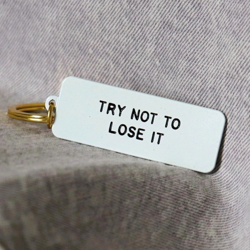 a rectangular keychain with the words "try not to lose it"