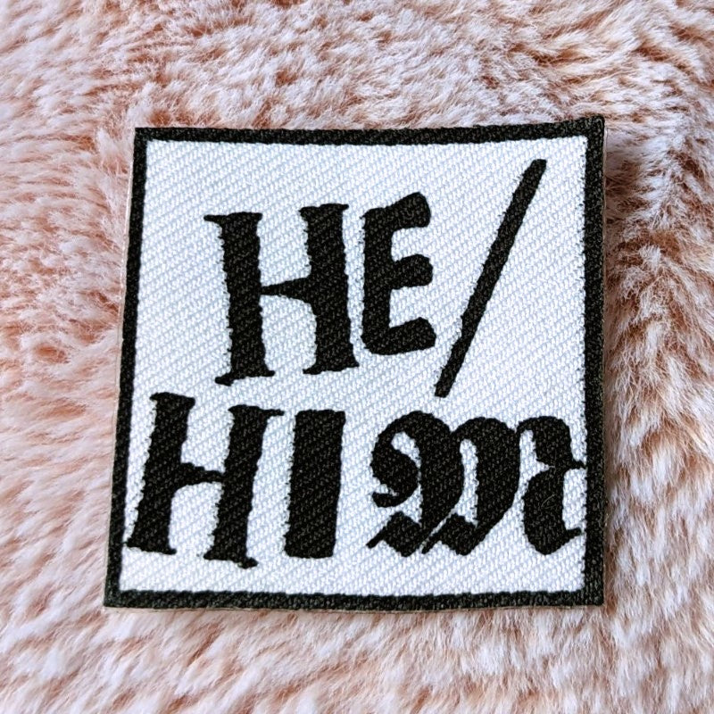 punk style iron-on canvas patch with the words "he/him"