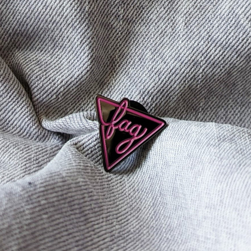 funny enamel pin of a pink triangle and the word "fag"