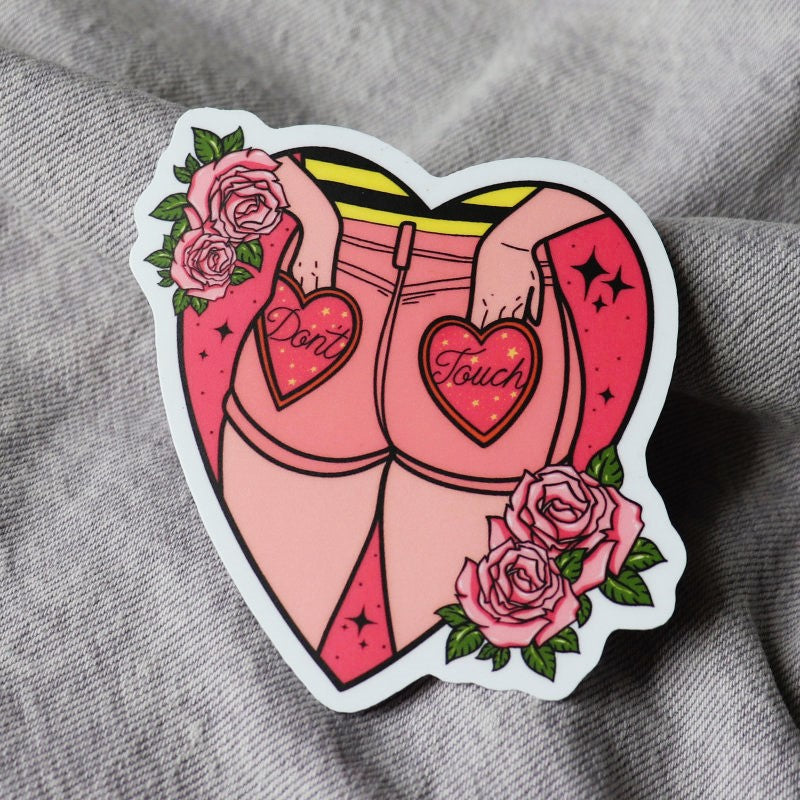 heart-shaped sticker of a person with hands in their back pockets, which read "dont touch"