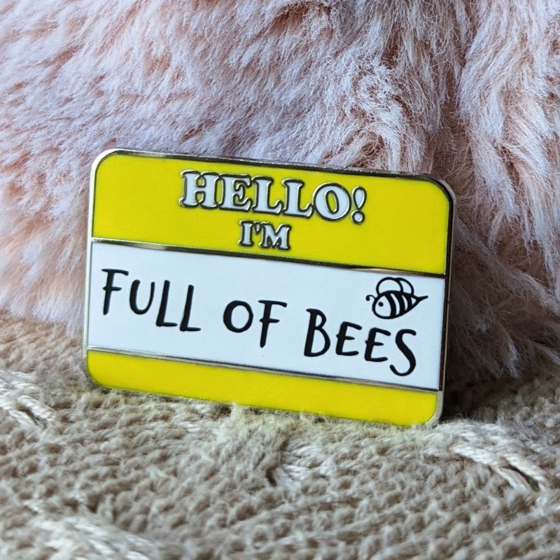 funny enamel pin of a name tag that says "hello -- I'm full of bees"