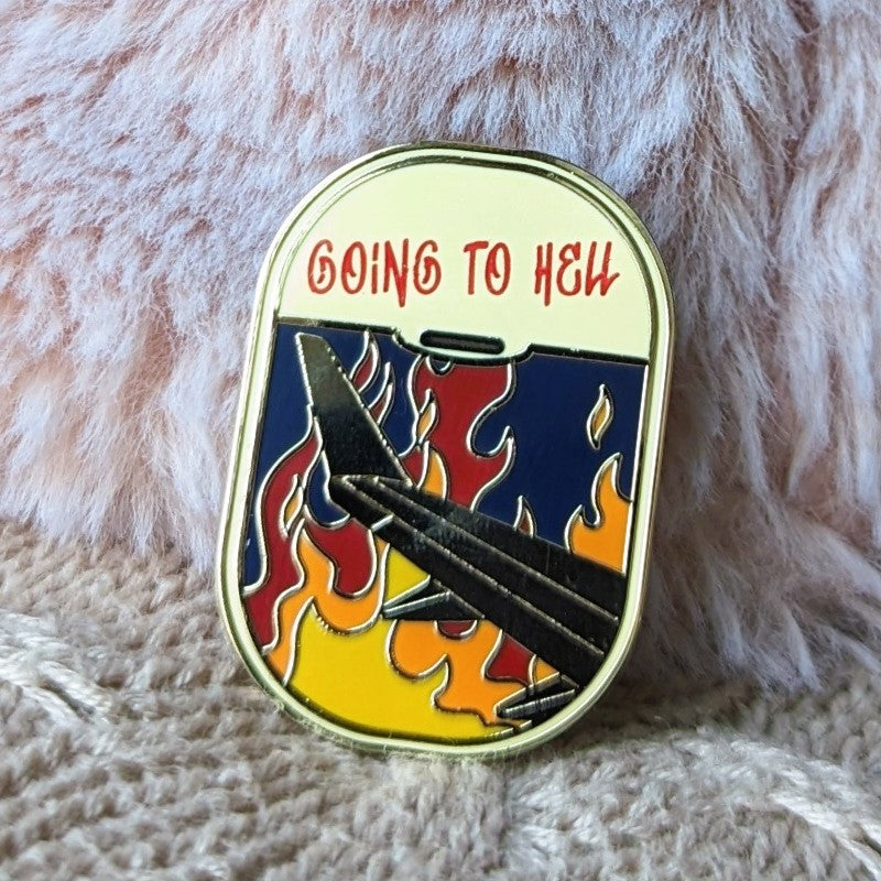 funny enamel pin of a plane flying over fire and the words "going to hell"