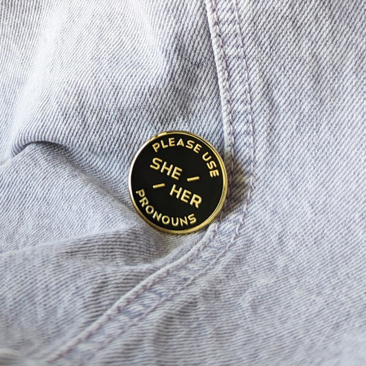 cool enamel pin that says "please use she/her pronouns"