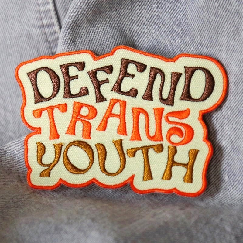 embroidered patch that says "defend trans youth"