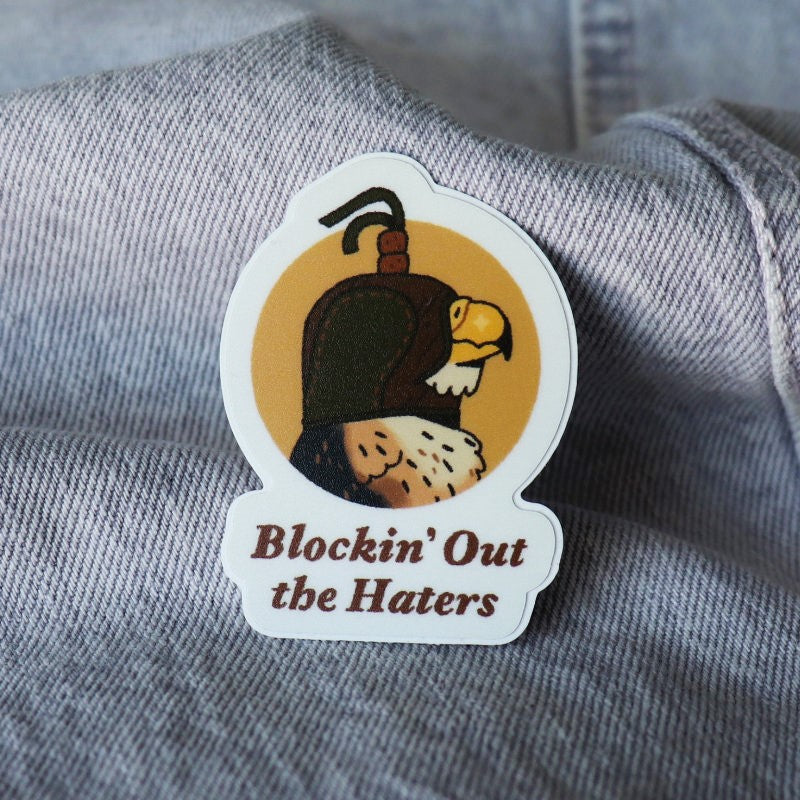 funny sticker of a hawk wearing a falconry hood and the words "blockin' out the haters"