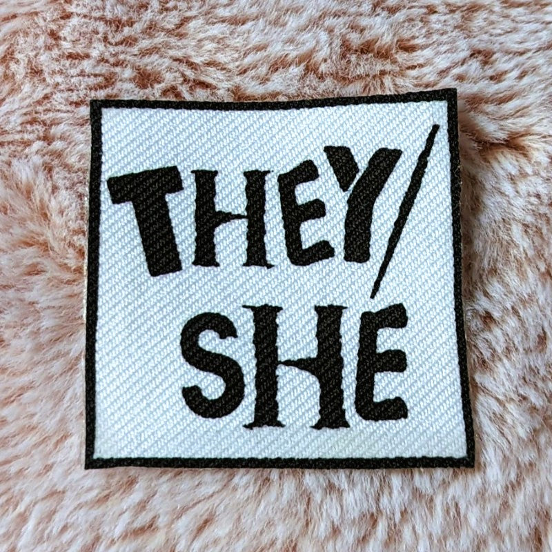 punk style iron-on canvas patch with the words "they/she"