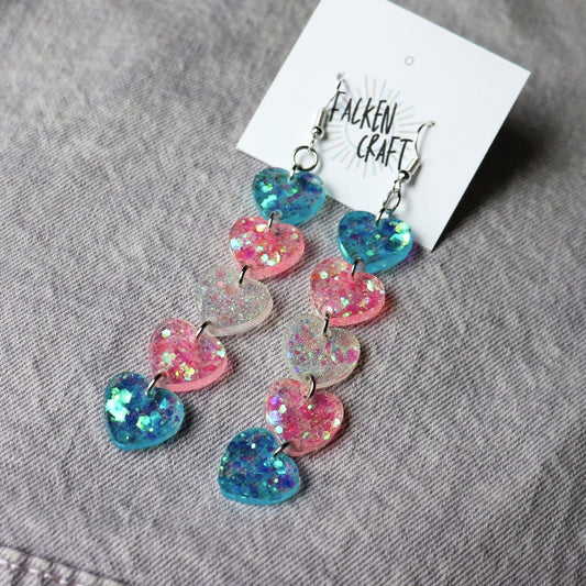 dangly earrings with hearts in the colors of the trans flag