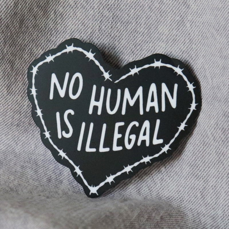 a heart-shaped sticker that says "no human is illegal"