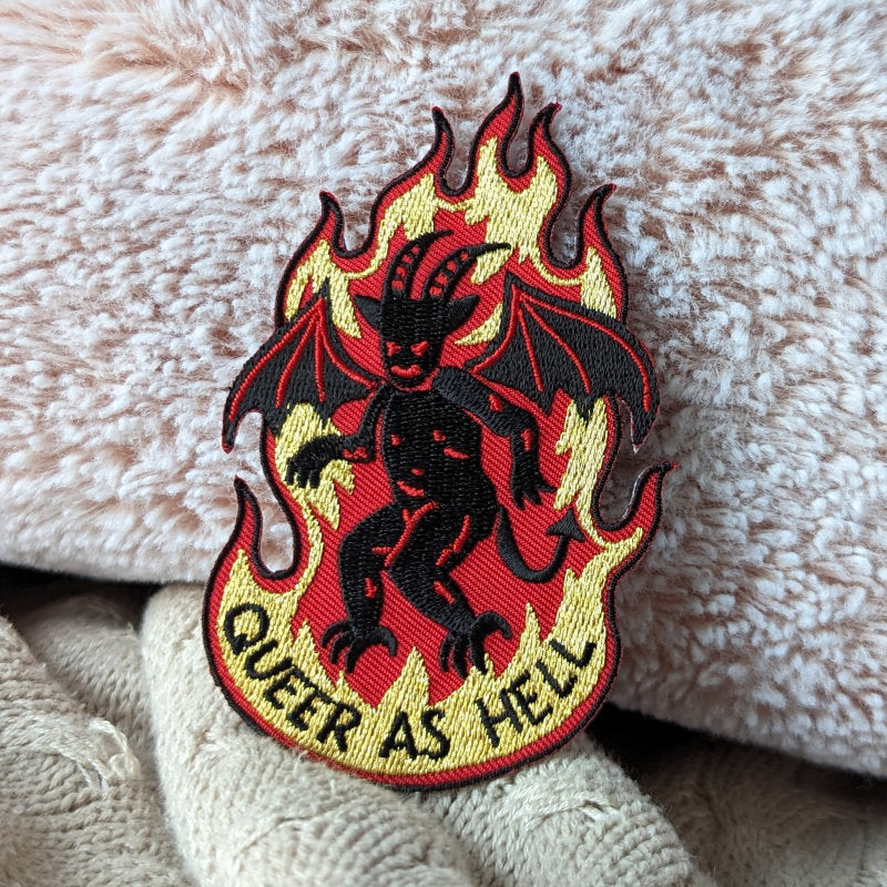 cool woven embroidered patch of a demon on fire and the words "queer as hell"