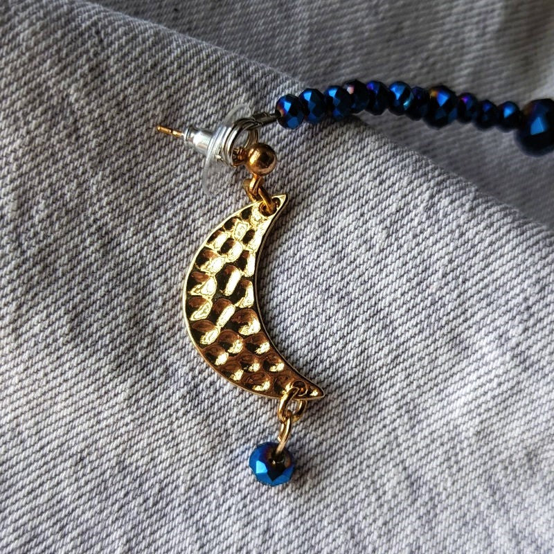 lapel pins with gold moons, and a string of blue beads between them.