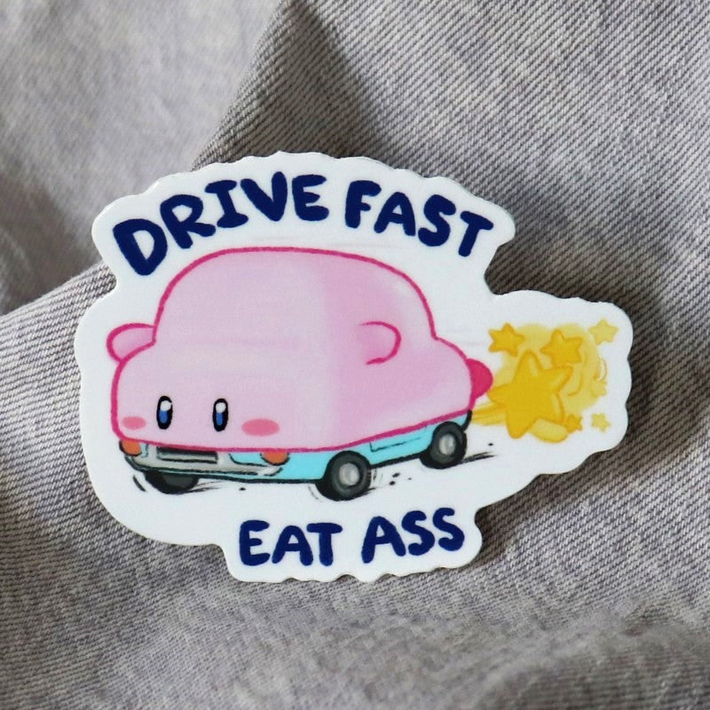 funny sticker featuring a pink video game character and the words "drive fast eat ass"