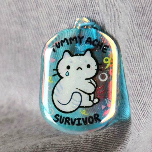 cute keychain of a kitty holding its tummy and the words "tummy ache survivor"