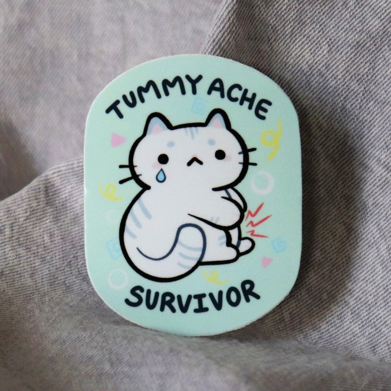 cute sticker featuring a cat with a stomach ache and the words "tummy ache survivor"