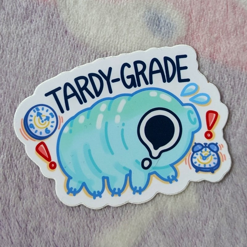 cute sticker of a tardigrade water bear, alarm clocks, and the word "tardy-grade"