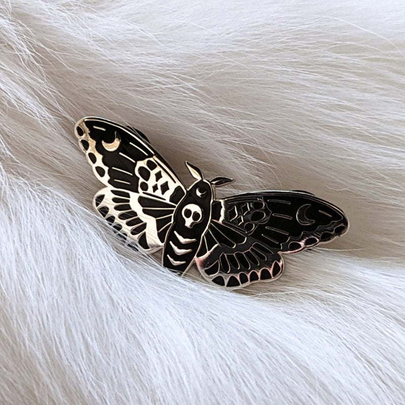 enamel pin of a moth with moons on its wings