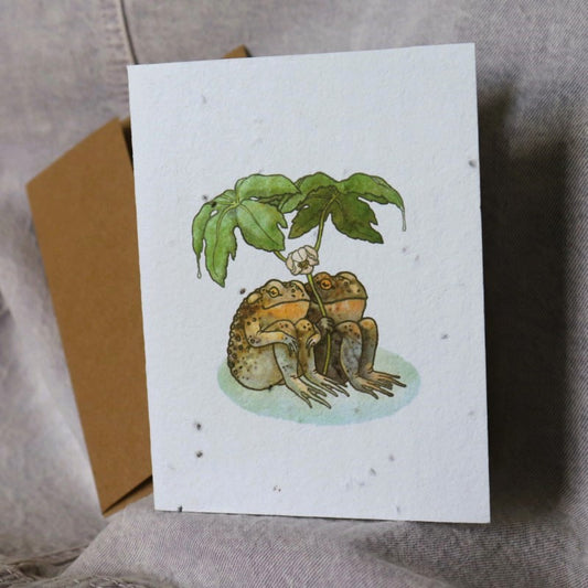 greeting card featuring a realistic illustration of two toads under a leaf