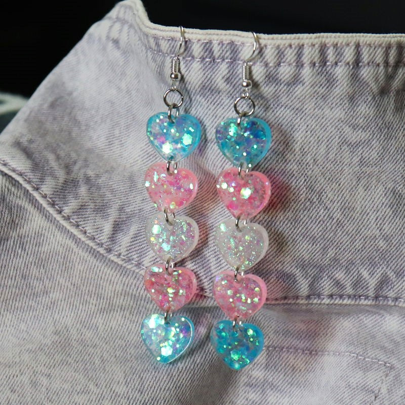 dangly earrings with hearts in the colors of the trans flag